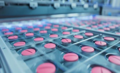 A close up image of trays of pink pills in production.